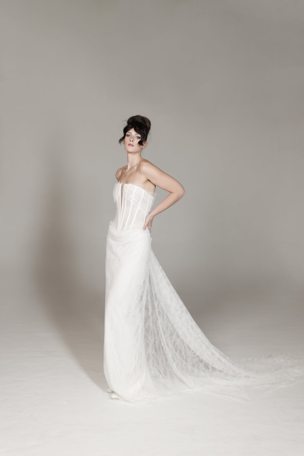 Woman in a white strapless gown with a long train on a plain background