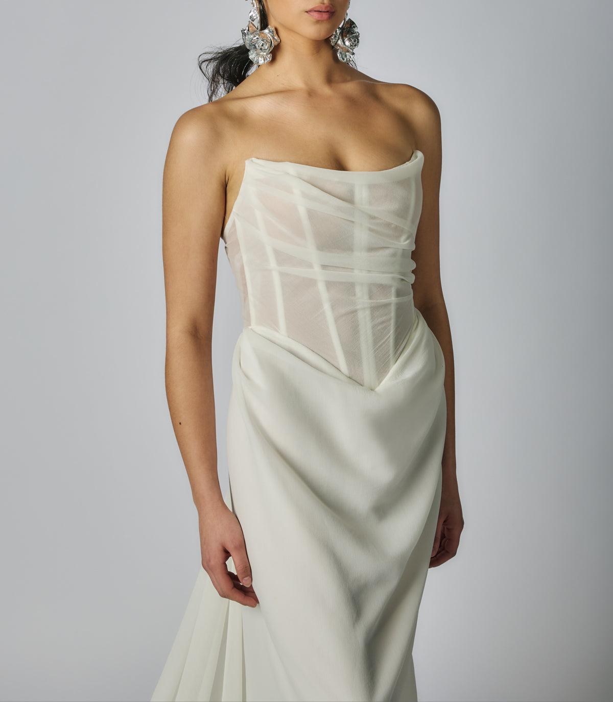 White strapless gown with sheer overlay on a plain background