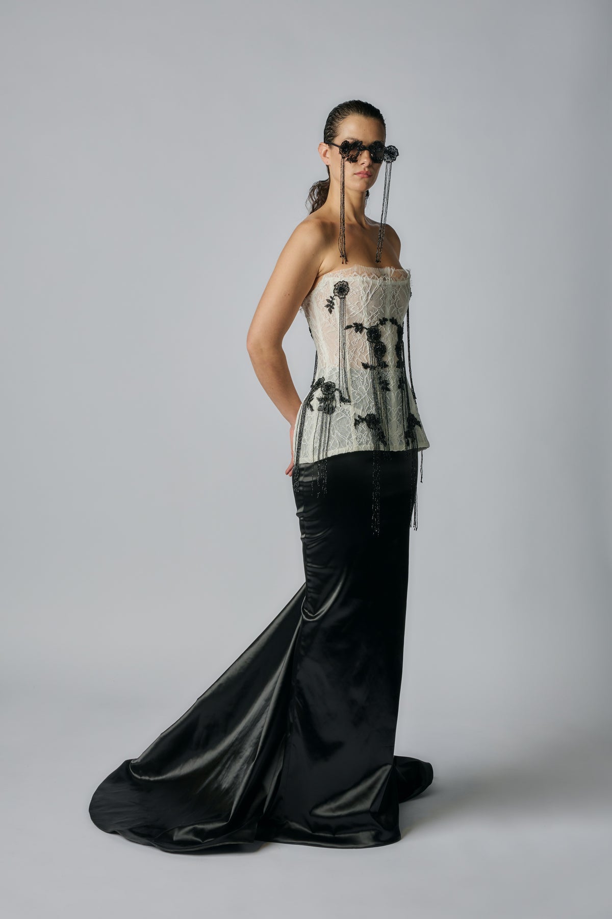 Woman wearing a strapless top with floral patterns and a long black skirt on a gray background