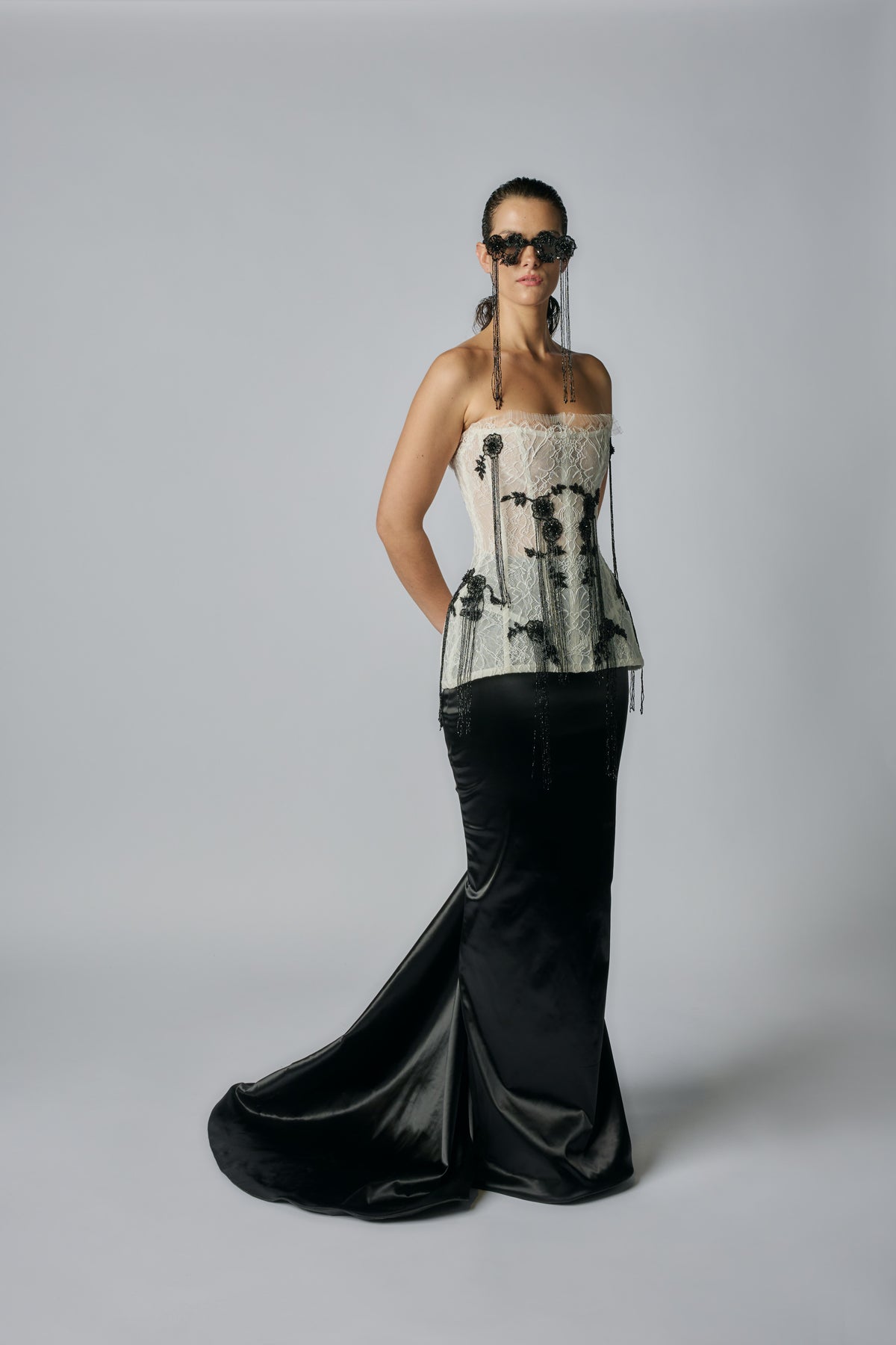 Woman wearing a strapless top with black and white pattern and a long black skirt on a gray background