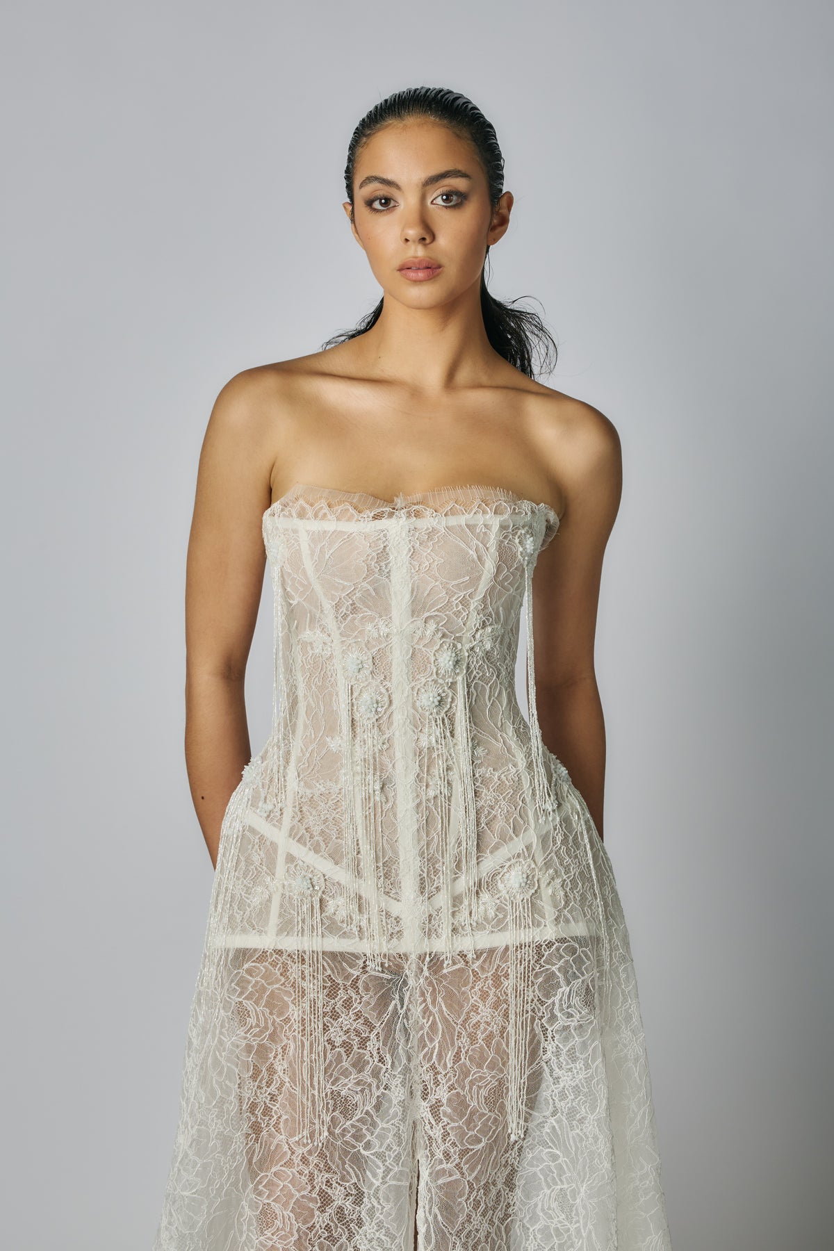 Woman wearing a strapless lace dress against a plain background