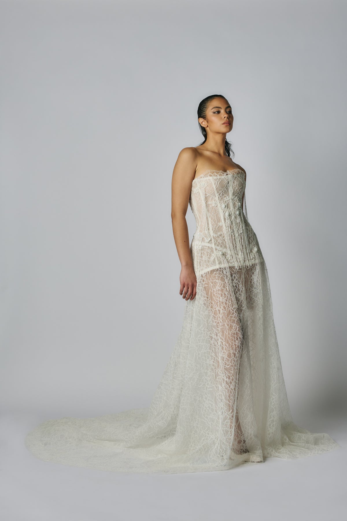 Woman wearing a lace wedding dress against a plain background
