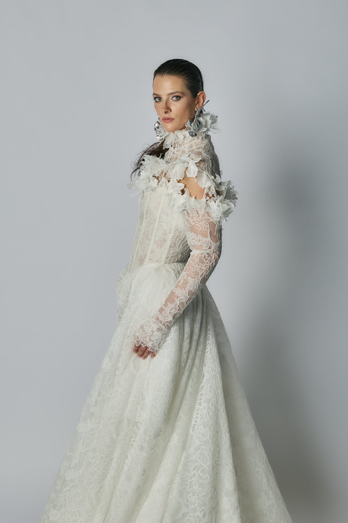 Woman wearing a white lace wedding dress against a gray background