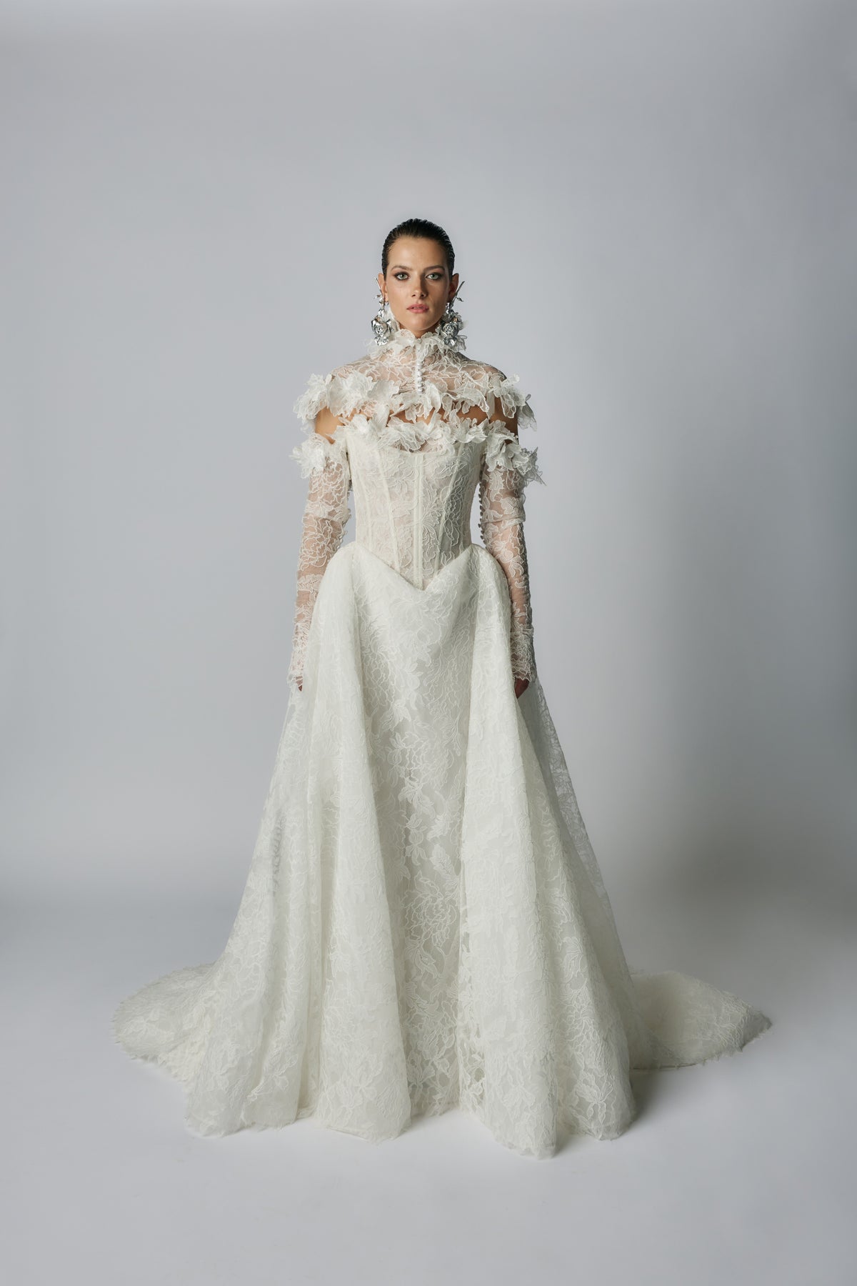 White lace wedding dress on a model against a plain background