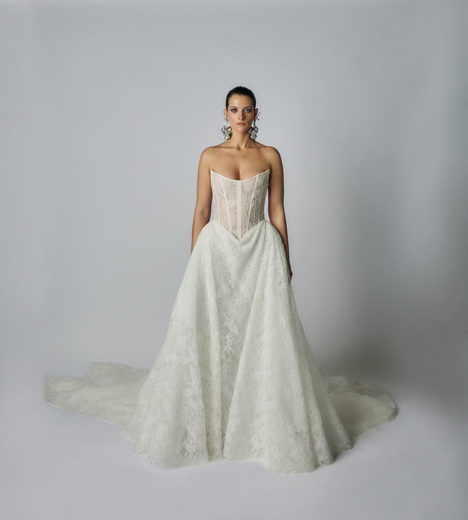Woman wearing a strapless lace wedding dress against a plain background