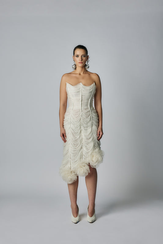 Woman wearing a strapless white wedding dress with ruffled details on a gray background